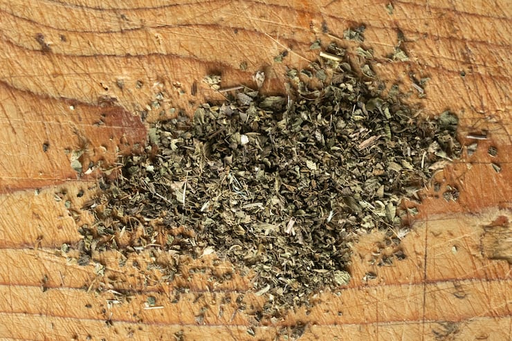 dried Oregano sprinkled on a wooden surface