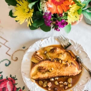 Two slices of Baked Mexican French Toast Torrejas on a white plate served with flowers on the side