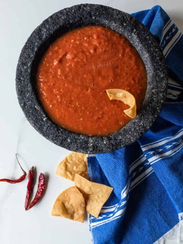 overhead shot of a bowl of chile de arbol spicy salsa with a chip sticking out of it