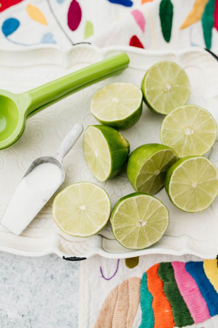 halved limes on a platter next to a citrus juicer