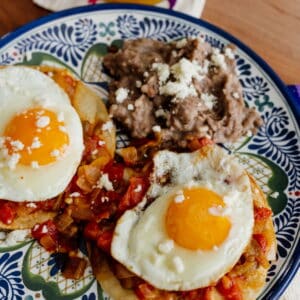 Authentic Huevos Rancheros recipe by Yvette Marquez-Sharpnack of Muy Bueno served with fried eggs, ranchero salsa, queso fresco, and refried beans on corn tortillas