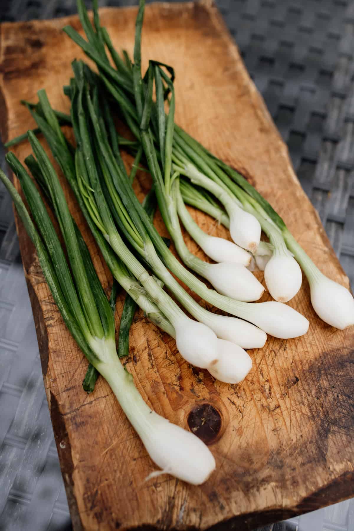 bunch of fresh spring onions on a wooden block