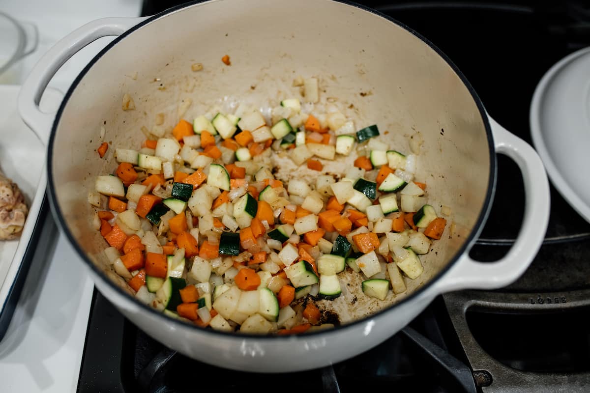 carrots, potatoes, onion, and zucchini chopped and cooking in white stock pot