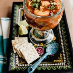 single serving of coctel de camarones on a black serving plate with a pile of saltines