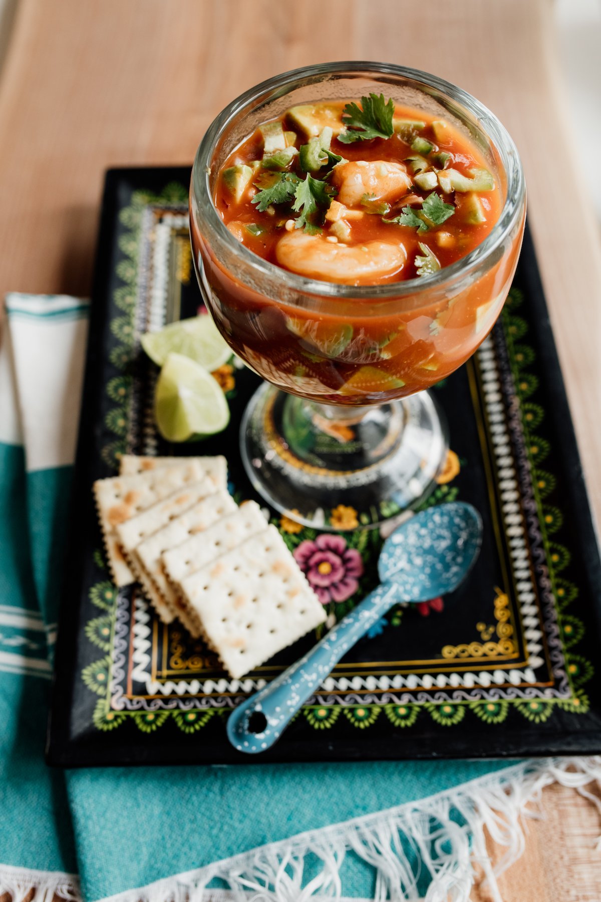 mexican shrimp cocktail (a.k.a. coctel de camarones) in a glass on a rectangular black plate with saltines.