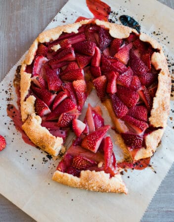 Rhubarb and Strawberry Crostata on a parchment sheet with a slice cut out