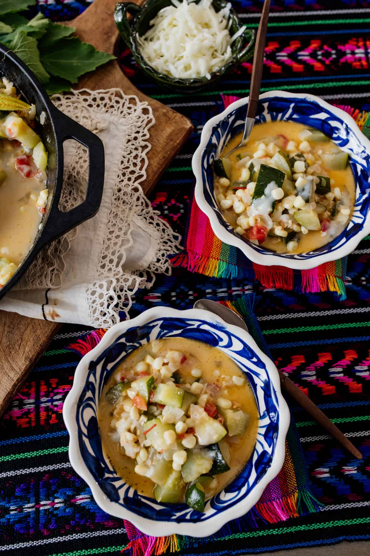 Calabacitas con Elote or Zucchini with Corn served in two bowls on a table covered with a beautiful cloth