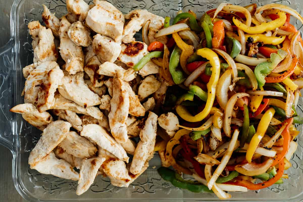 cooked chicken and bell peppers in a dish for fajitas