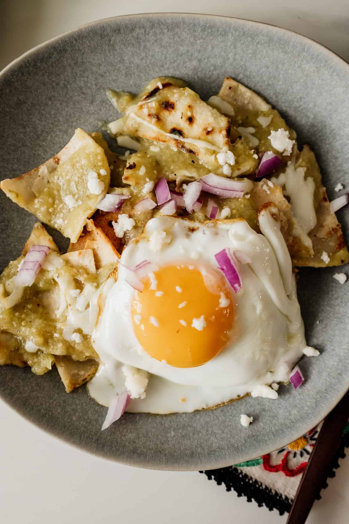 chilaquiles verde on a gray plate topped with a fried egg