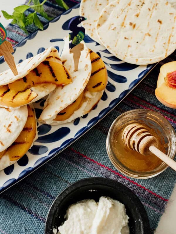 grilled peaches ricotta tortilla appetizer on a blue and white platter with a side of ricotta and honey on the side