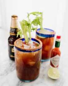 two Michelada beer cocktails with a beer and tabasco on the side