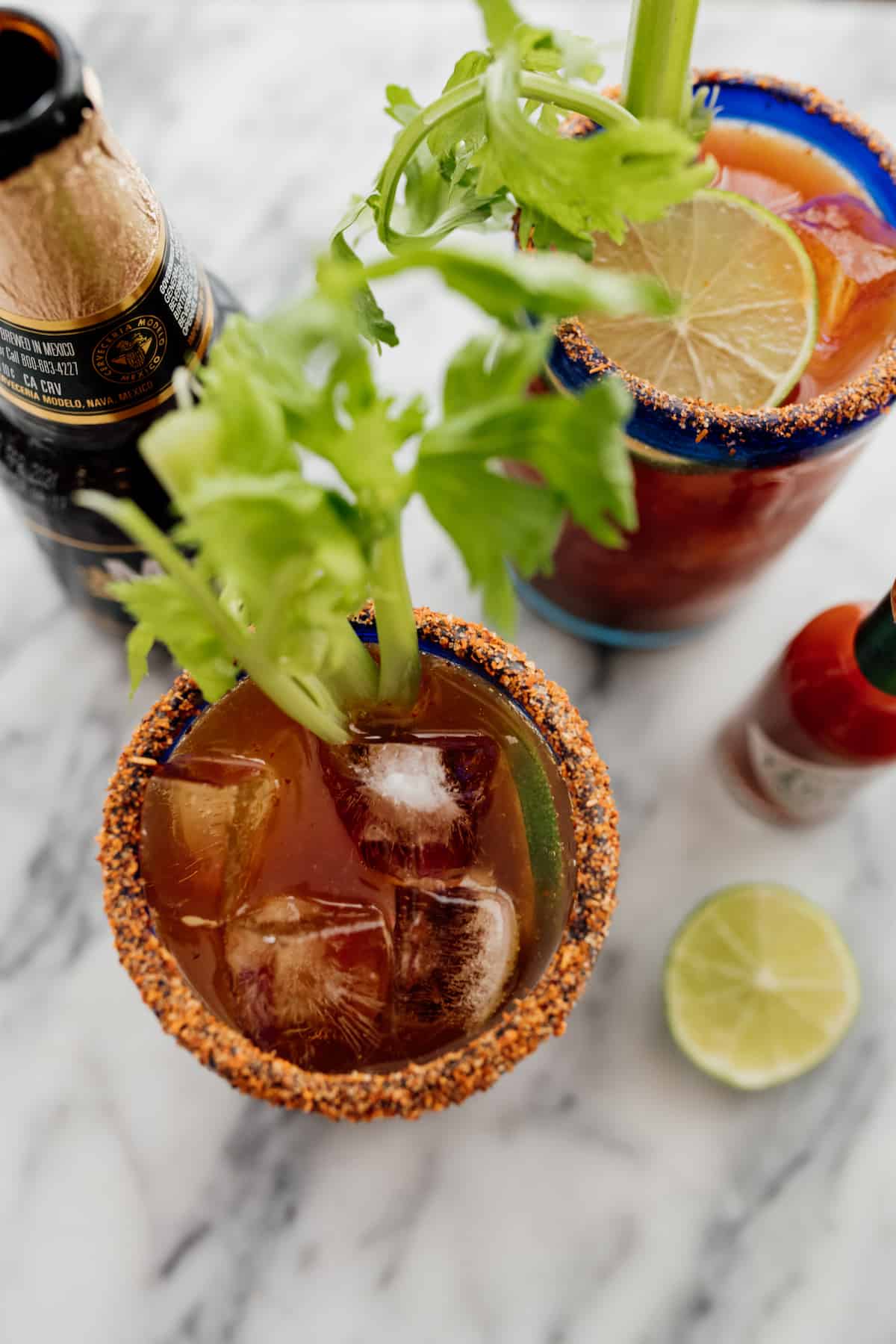 top down inside glasses of a michelada with celery stalks