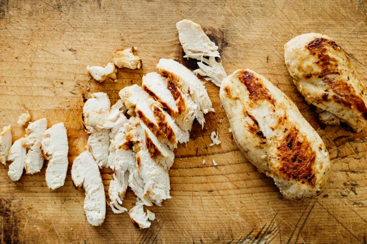 sliced grilled chicken on a wooden board