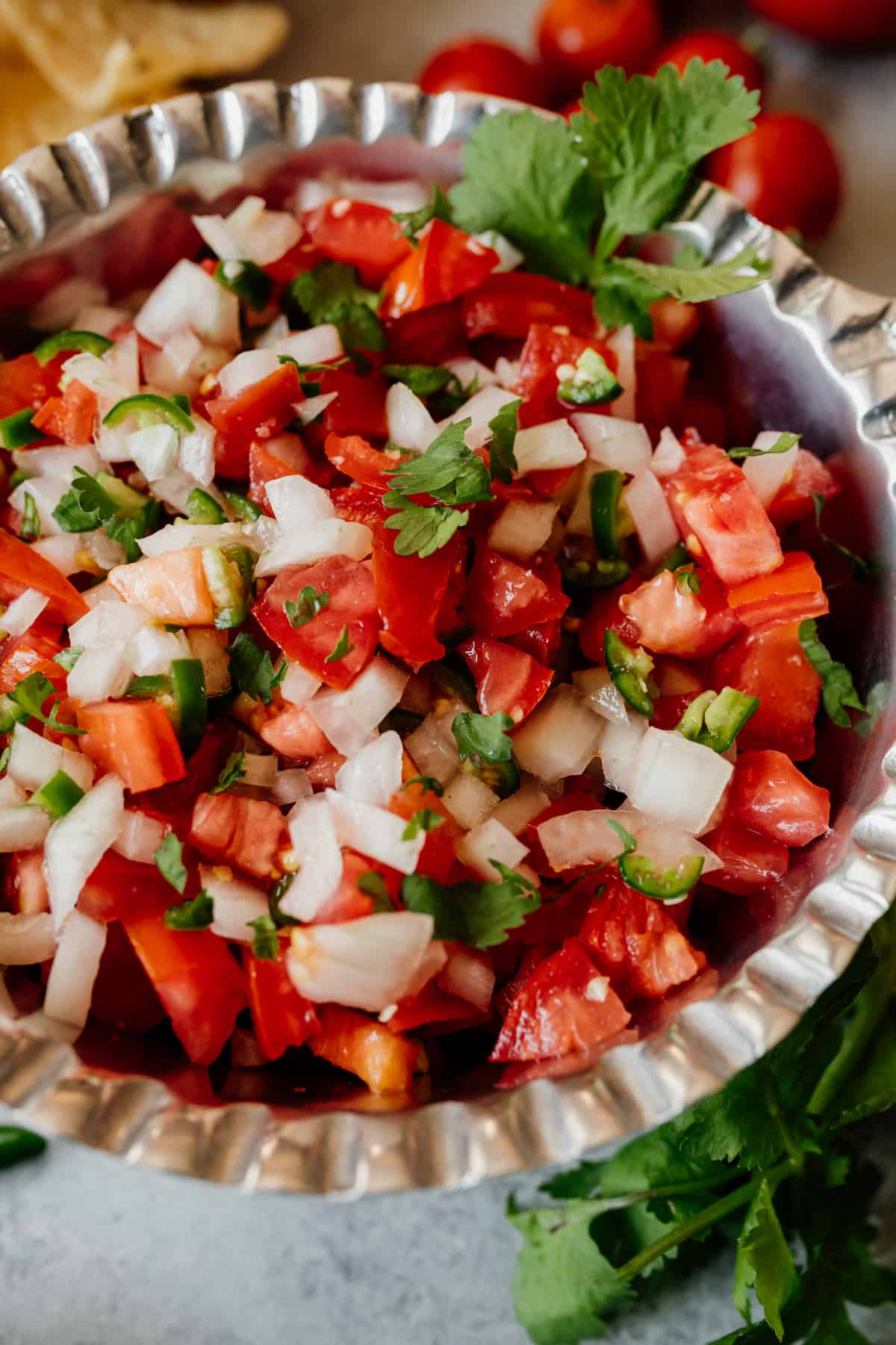 Close-up view of this simple pico de gallo, aka salsa bandera or chopped tomato salad, in a silver bowl to be served as an appetizer with tortilla chips