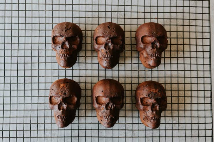 Six freshly baked Mexican Chocolate Skull Cakes cooling on a wire rack.
