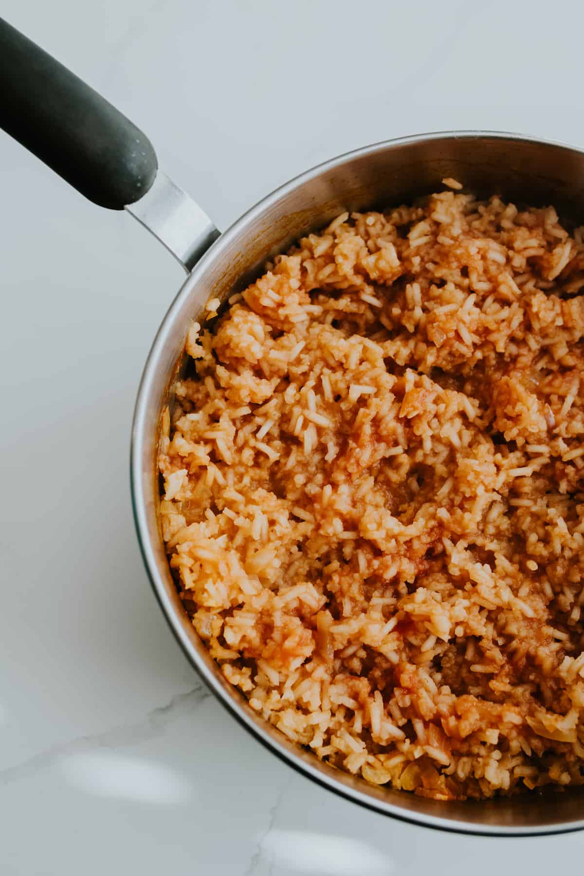 cooked Mexican rice in a skillet on a marble countertop