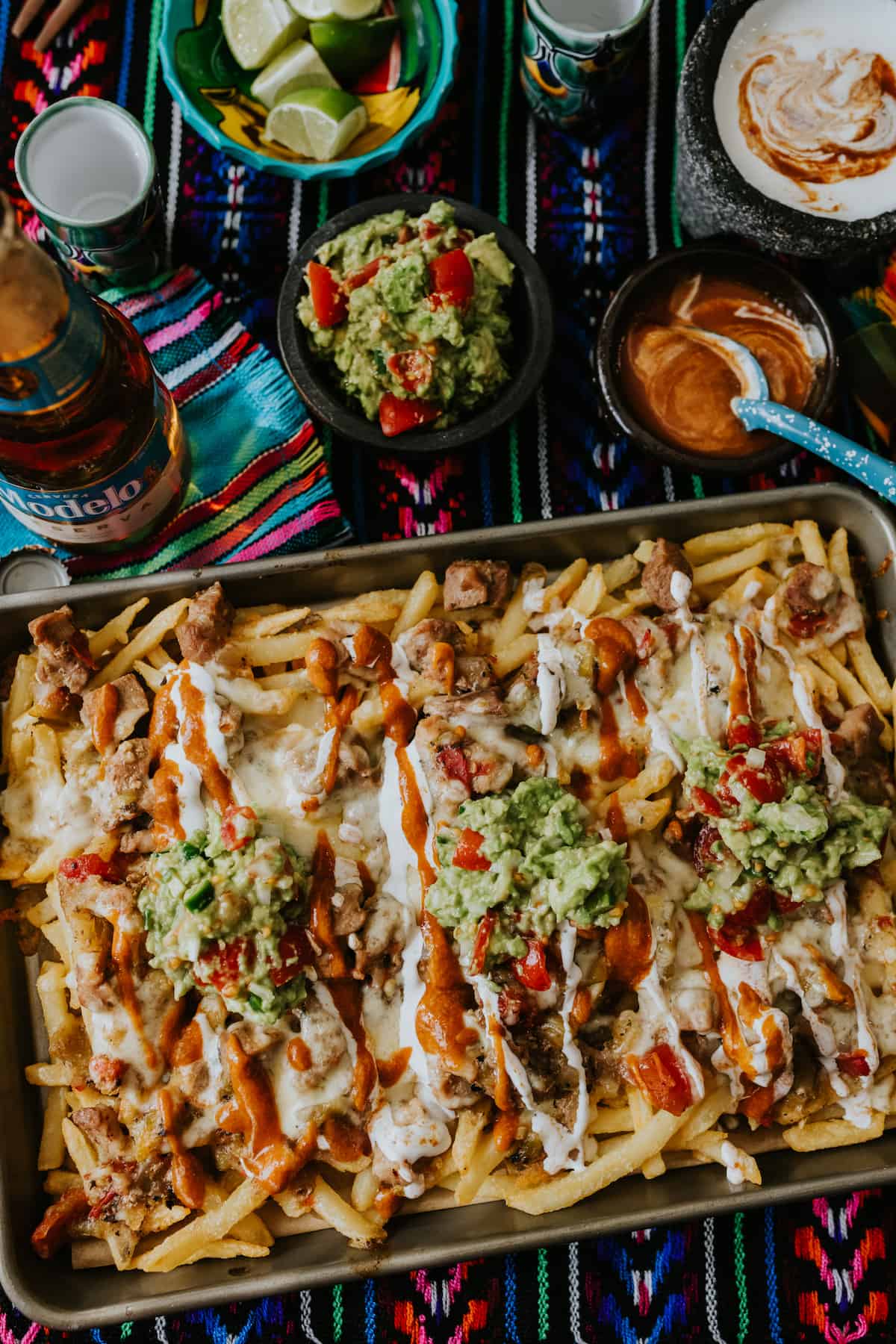baking sheet with baked fries loaded with pork green Chile, cheese, guacamole