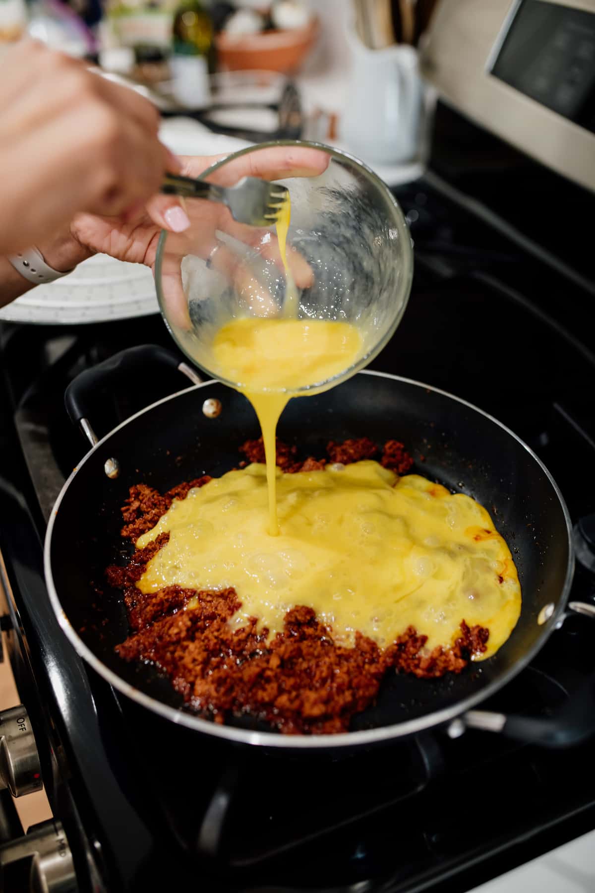 adding eggs to cooked Mexican Chorizo in a skillet