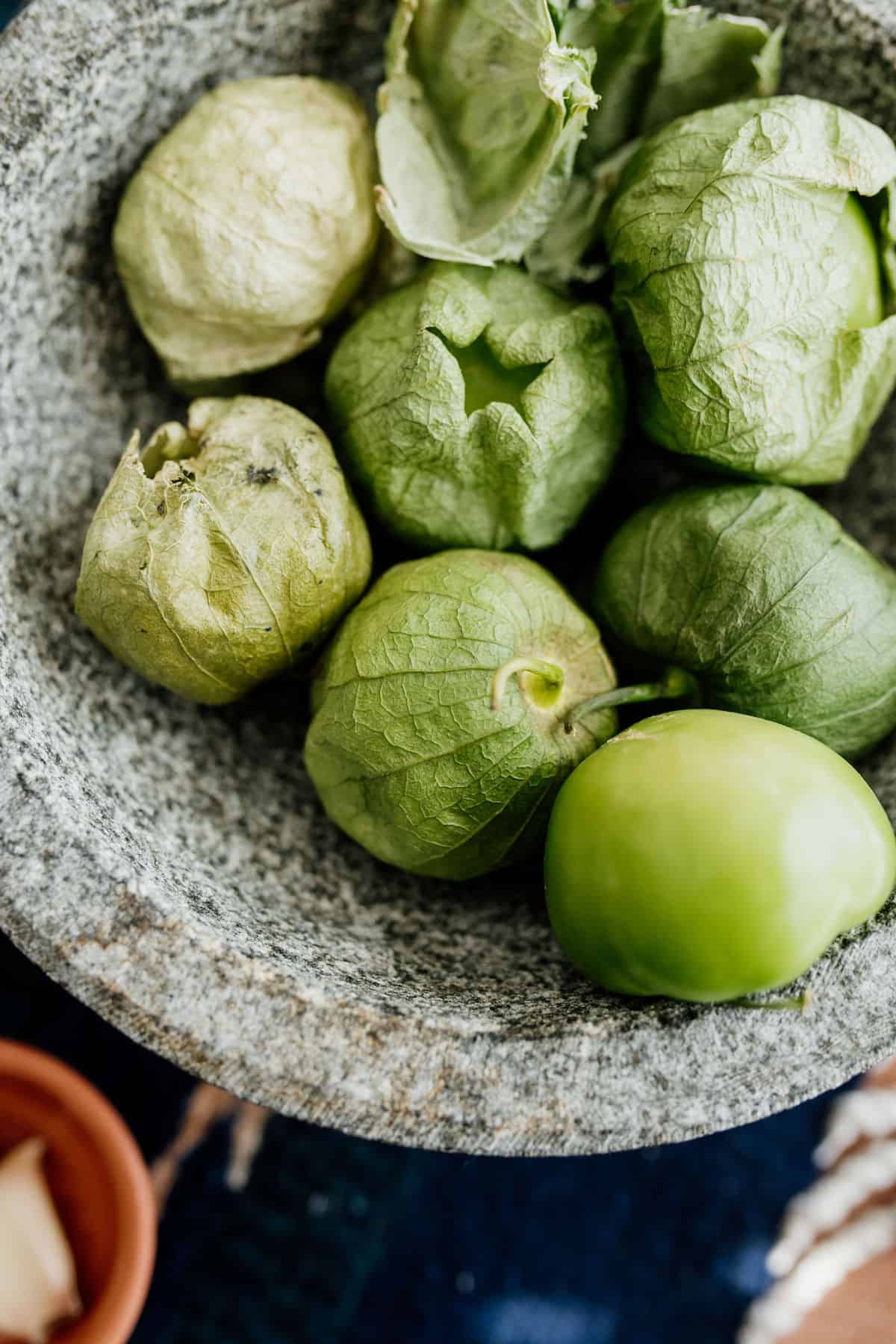a closeup of green tomatillos aka husked tomatoes in a molcajete.