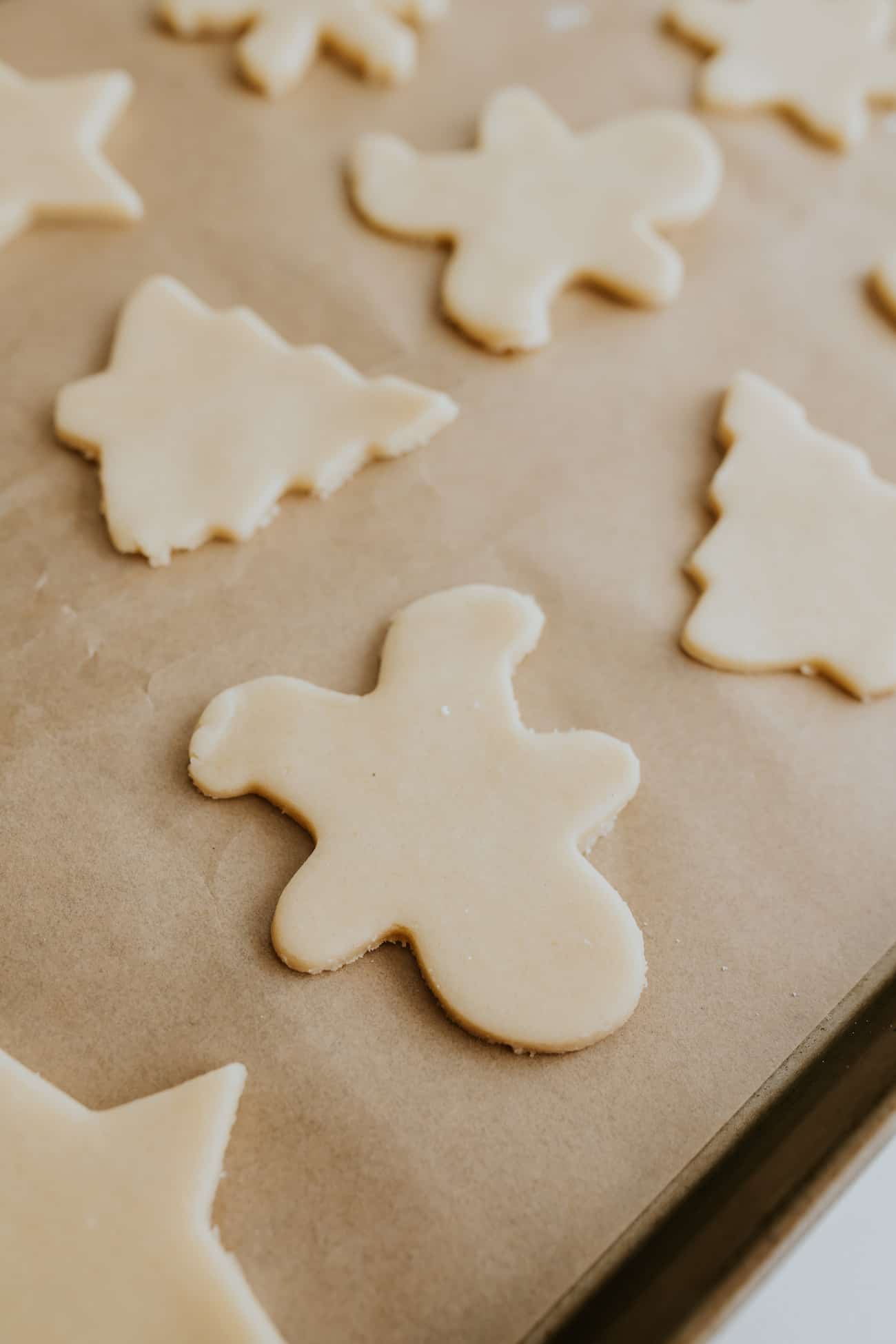 unbaked christmas cookie cutouts on a parchment lined sheet.