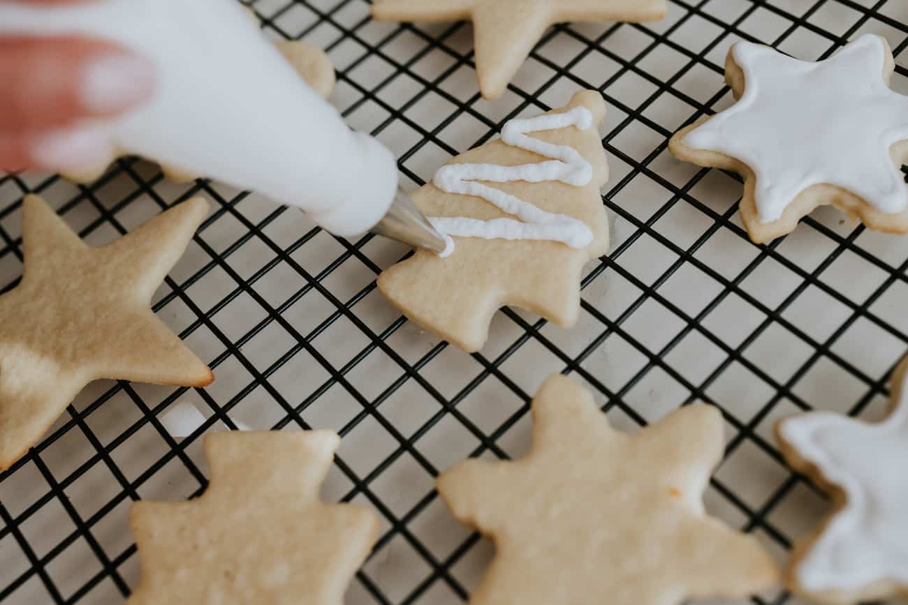 piping frosting onto a tree shaped christmas sugar cookie.