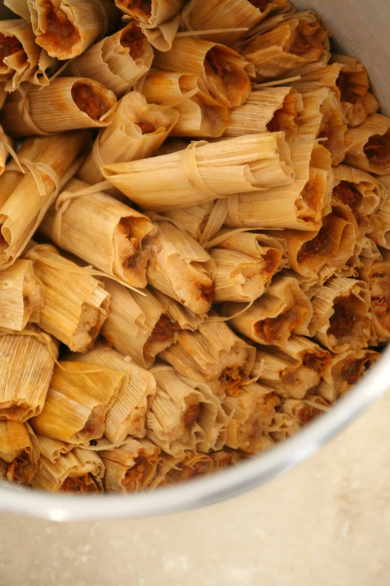 a large steamer filled tightly with cooked red Chile and pork tamales.