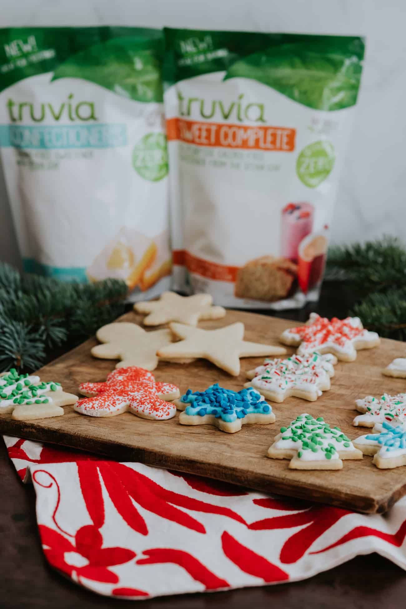 wooden platter of decorated christmas cookies with a bag of truvia powdered sugar alternative and regular sugar alternative.