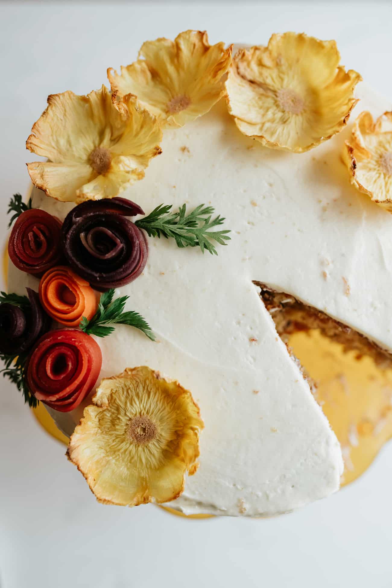 overhead shot of carrot cake decorated with dried pineapple flowers.