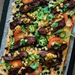 carne asada taco pizza on a baking sheet.
