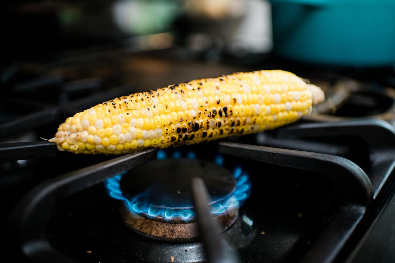 Corn being charred on the gas stovetop.