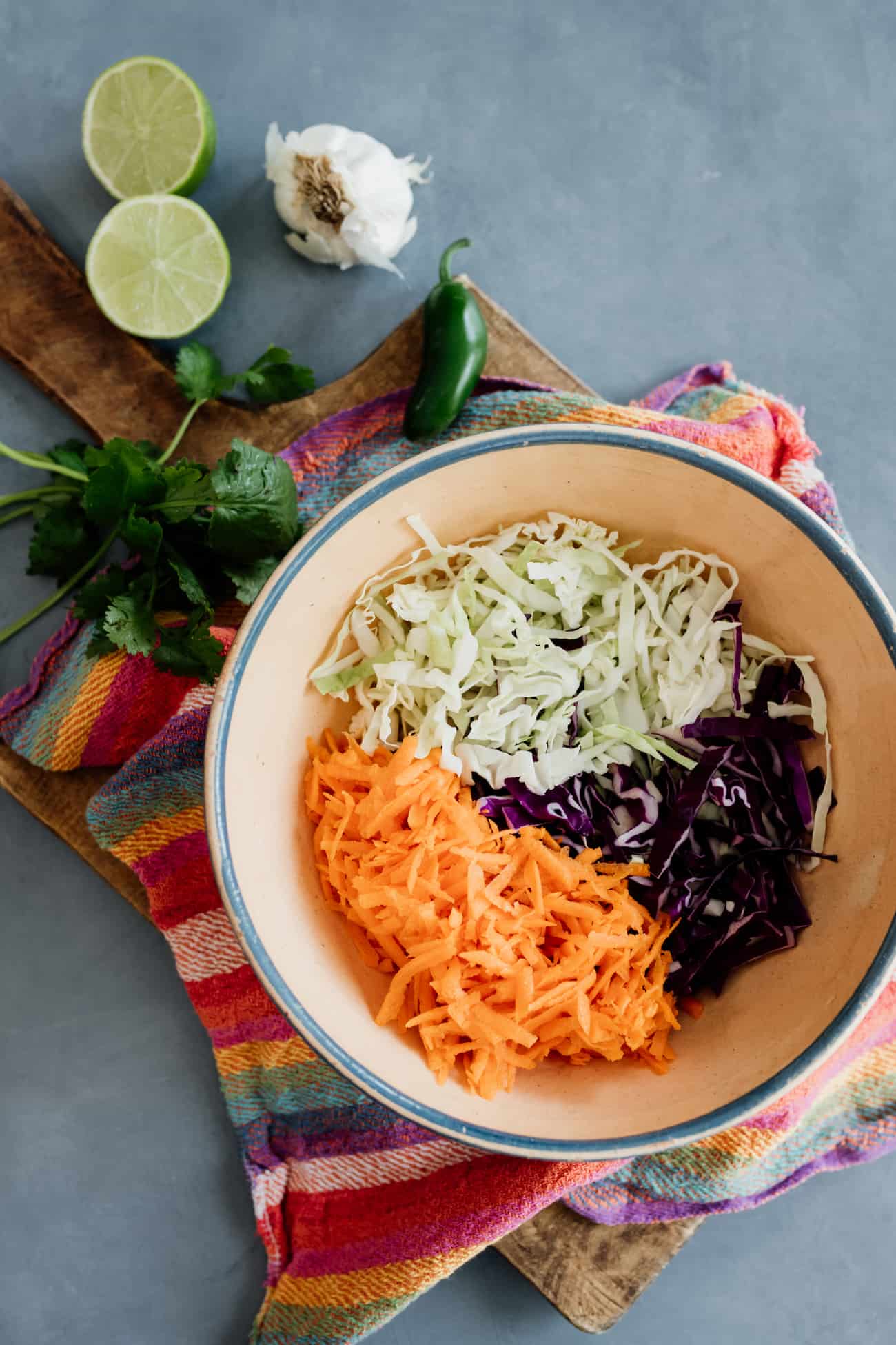 shredded green and purple cabbage and grated carrots in a bowl for making cole slaw.