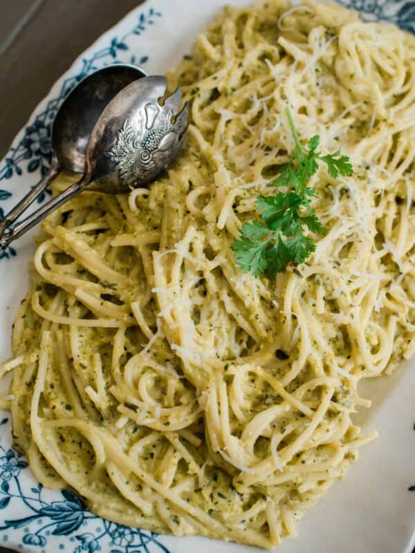 Espagueti Verde served on a cute plate with a metal spoon on top.