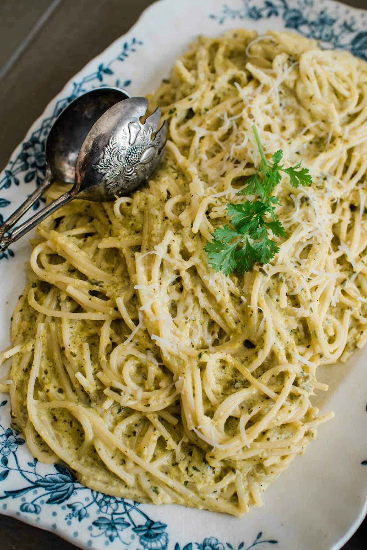 Espagueti Verde served on a cute plate with a metal spoon on top.