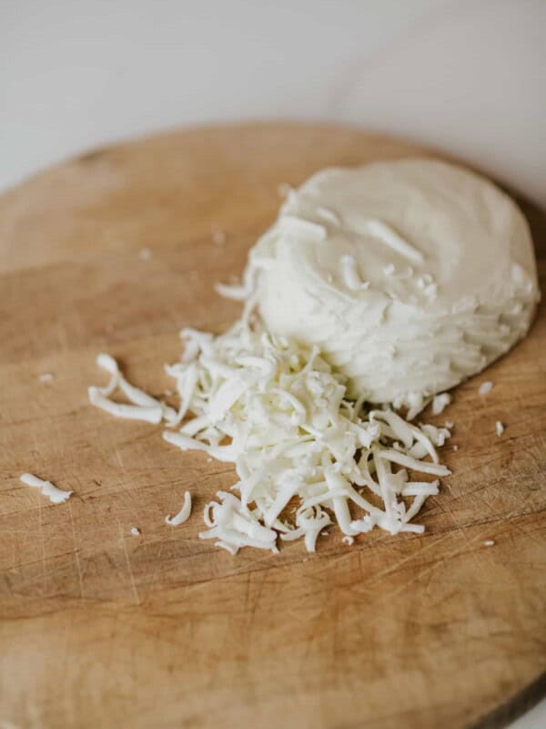 grated shredded Oaxaca cheese on a wooden board.