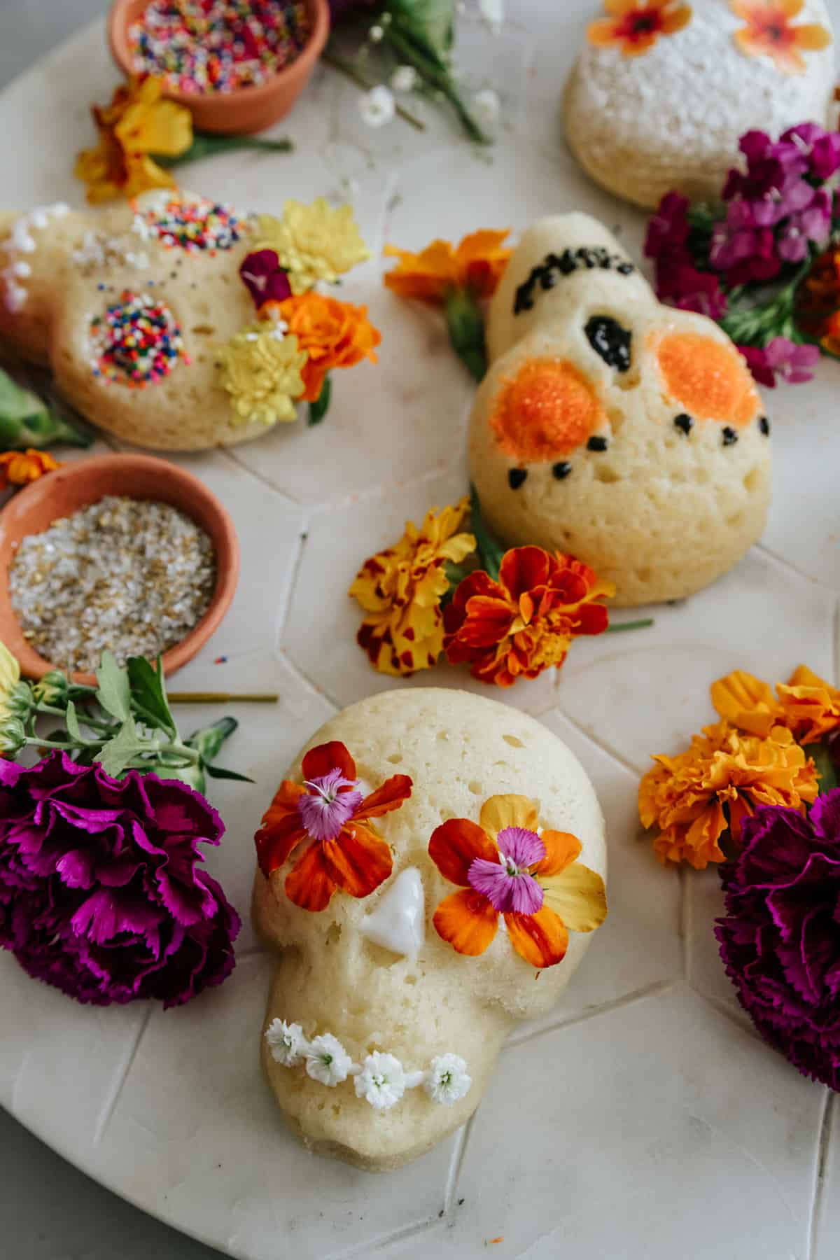 mini lemon sugar skull cake with edible orange flowers for eyes and edible tiny white flowers for a mouth.