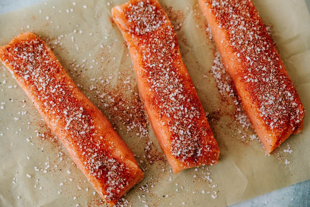 salmon fillets on a parchment-lined sheet tray and sprinkled with taco seasonings. 