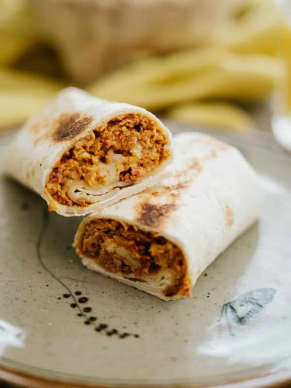 speckled grey plate with egg and cheese breakfast burrito split in half.
