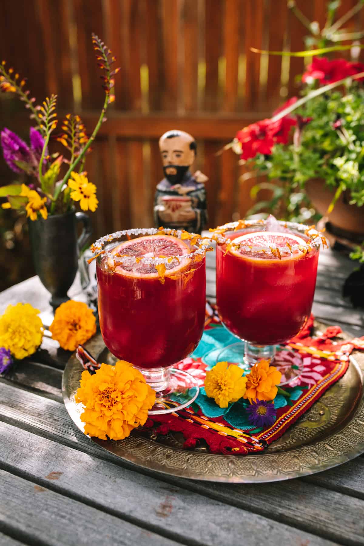 marigold surrounding two blood orange margaritas with marigold petals rim.