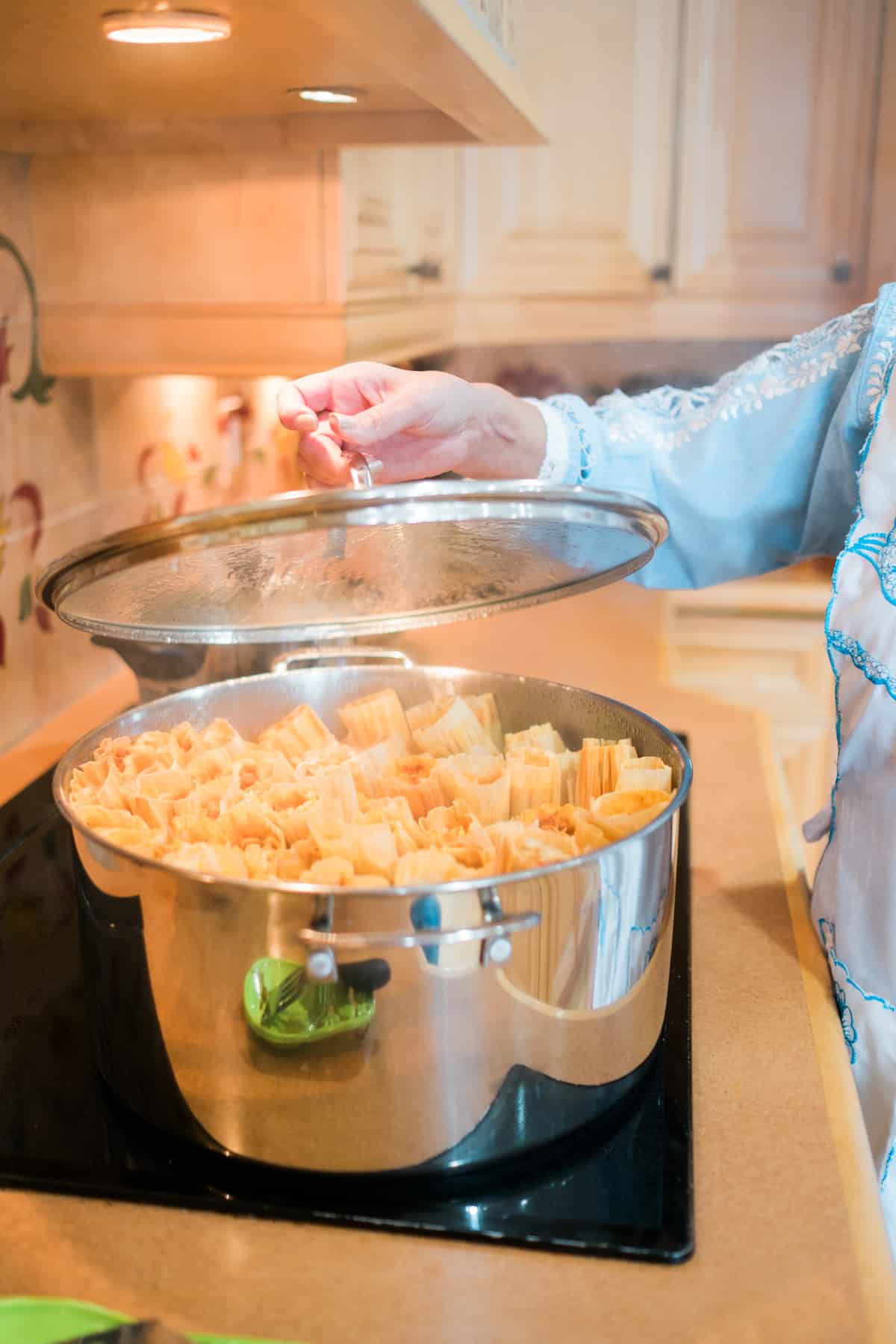 large tamale-steaming pt packed to the brim with tamales on a stovetop.