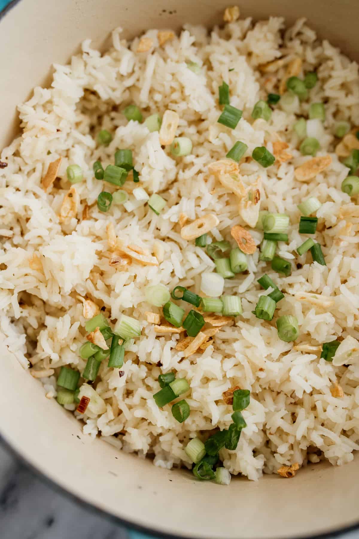 closeup overhead shot of garlic butter rice topped with golden garlic chips and green onions. 