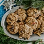 oblong silver serving platter with a batch of mexican hot chocolate oatmeal cookies garnished with branches of pine tree.