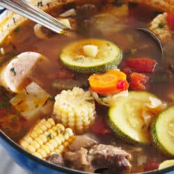 Overhead view of Caldo de Res, a traditional Mexican beef soup with vegetables, in a blue enameled cast iron Dutch oven.