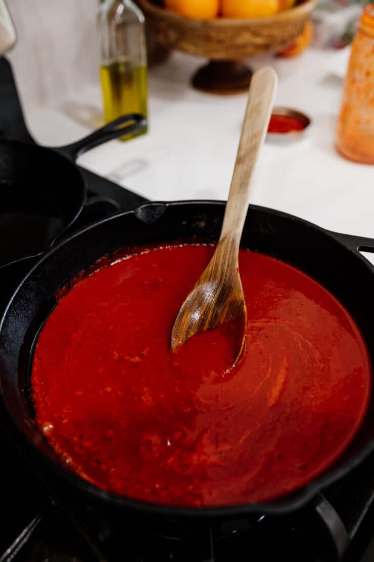 Homemade red chile sauce simmering in a cast-iron skillet for Chilaquiles Rojos, a classic Mexican breakfast.