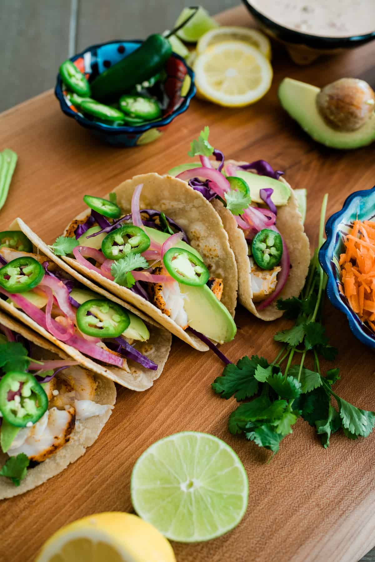 Lemon butter tilapia tacos beautifully presented on a wooden board.