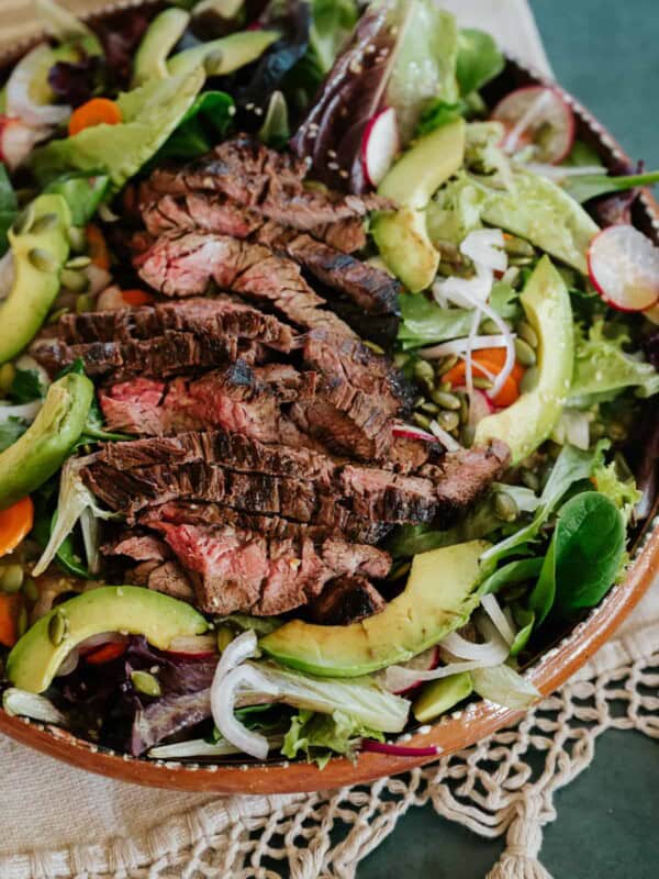 closeup shot of carne asada salad in a terracotta serving bowl.