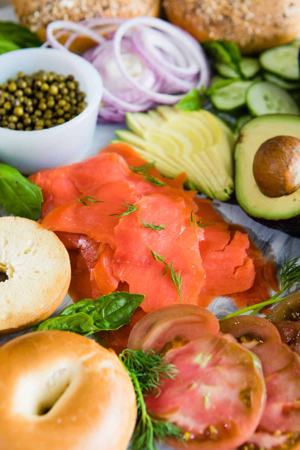 closeup shot of smoked salmon pieces topped with dill on a bagel platter.