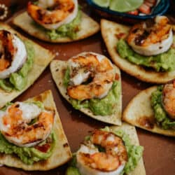 Easy Grilled BBQ Shrimp Appetizer with Baked Flour Tortilla Chips and guacamole on a terracotta plate.