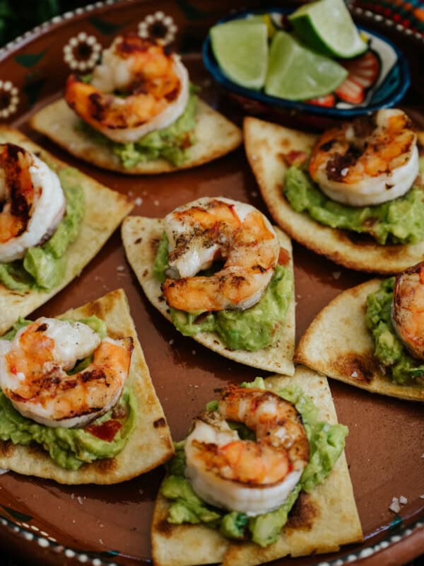 Easy Grilled BBQ Shrimp Appetizer with Baked Flour Tortilla Chips and guacamole on a terracotta plate.