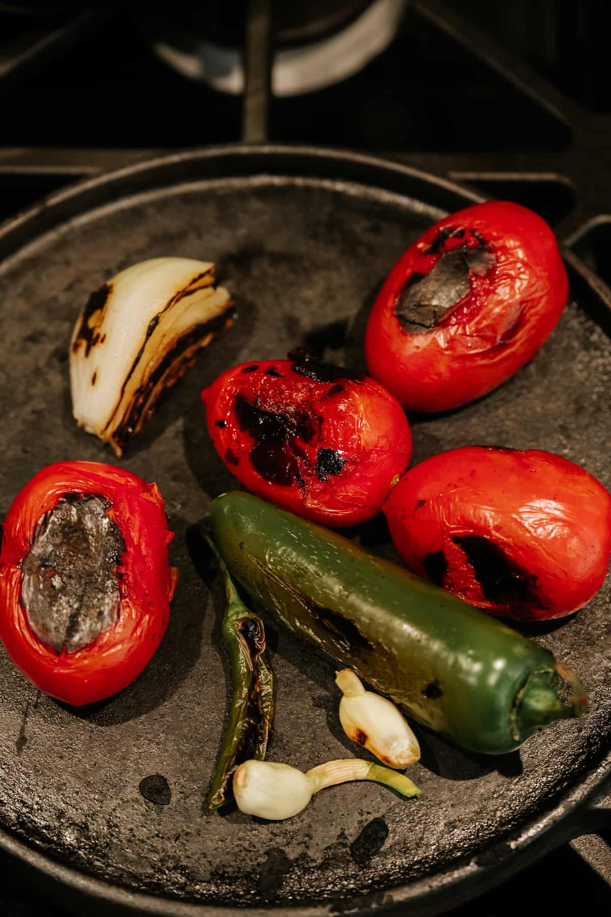 roasting jalapenos, tomatoes, garlic, and onion on a comal for making authentic Mexican salsa roja. 