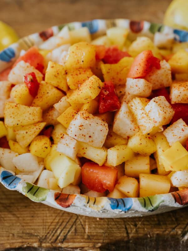 mexican fruit salad in a colorful serving bowl garnished with tajin.